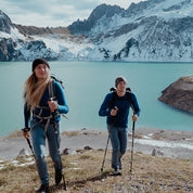 Zwei Wanderer tragen das Merino Langarm Shirt Damen 230 g/m2 von Alpin Loacker, ideal für Outdoor-Aktivitäten, vor einer alpinen Seen- und Berglandschaft.