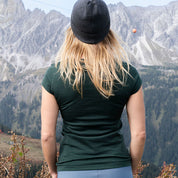 Person von hinten in alpiner Landschaft, trägt 100% Merino T-Shirt Damen 180g/m2, perfekt für Outdoor-Aktivitäten. Ideal für Komfort und Funktionalität bei jedem Wetter.