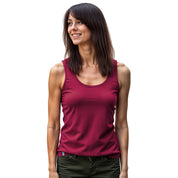 Junge Frau im Merino Tank Top Damen 150g/m2, lächelnd. Ideal für Outdoor-Abenteuer, bietet optimalen Klima- und Tragekomfort durch CORESPUN-Technologie.