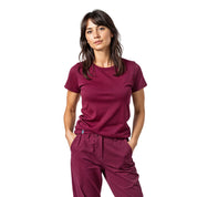 Junge Frau in burgundroten Scrubs, repräsentiert das 100% Merino T-Shirt Damen 180g/m2, ideal für Outdoor-Aktivitäten und Alltag, mit höchsten Komfort und Funktionalität.