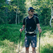 Mann auf Waldweg trägt Merino V-Neck T-Shirt Herren, ideal für Outdoor-Aktivitäten. Kombiniert Stil und Funktionalität, perfekt für Abenteurer.