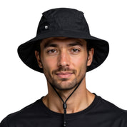 Junger Mann trägt den leichten Regenhut von Alpin Loacker, ideal für Outdoor-Aktivitäten, aus 100% recyceltem Polyester, mit Kinnriemen und wasserdichtem, atmungsaktivem Material.