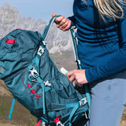Person steckt Gegenstand in Mesh-Seitentasche eines 35 Liter Wanderrucksacks Herren & Damen von Alpin Loacker, ideal für Outdoor-Abenteuer.