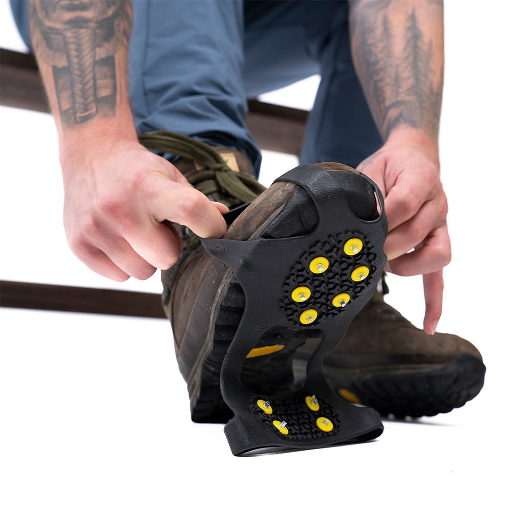 Nahaufnahme von Spikes für Schuhe von Alpin Loacker, die über einen robusten Wanderschuh gezogen werden, um auf Eis und Schnee sicheren Halt zu bieten.