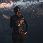 Wanderin mit Alpin Loacker Lotus 25 2.0 Rucksack, blickt auf alpines Panorama. Leichter, wasserdichter Rucksack für Outdoor-Abenteuer.