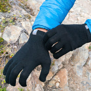 Person im Freien, die Merino Handschuhe Damen & Herren, Classic, anzieht; ideale Wahl für Outdoor-Abenteuer mit Wärme und Geschicklichkeit, erhältlich bei Alpin Loacker.