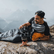 Mann nutzt Alpin Loacker Camping Gaskocher Set auf Berggipfel, umgeben von Nebel. Ideales ultraleichtes Kochset für Outdoor-Abenteuer und schnelle Mahlzeiten.