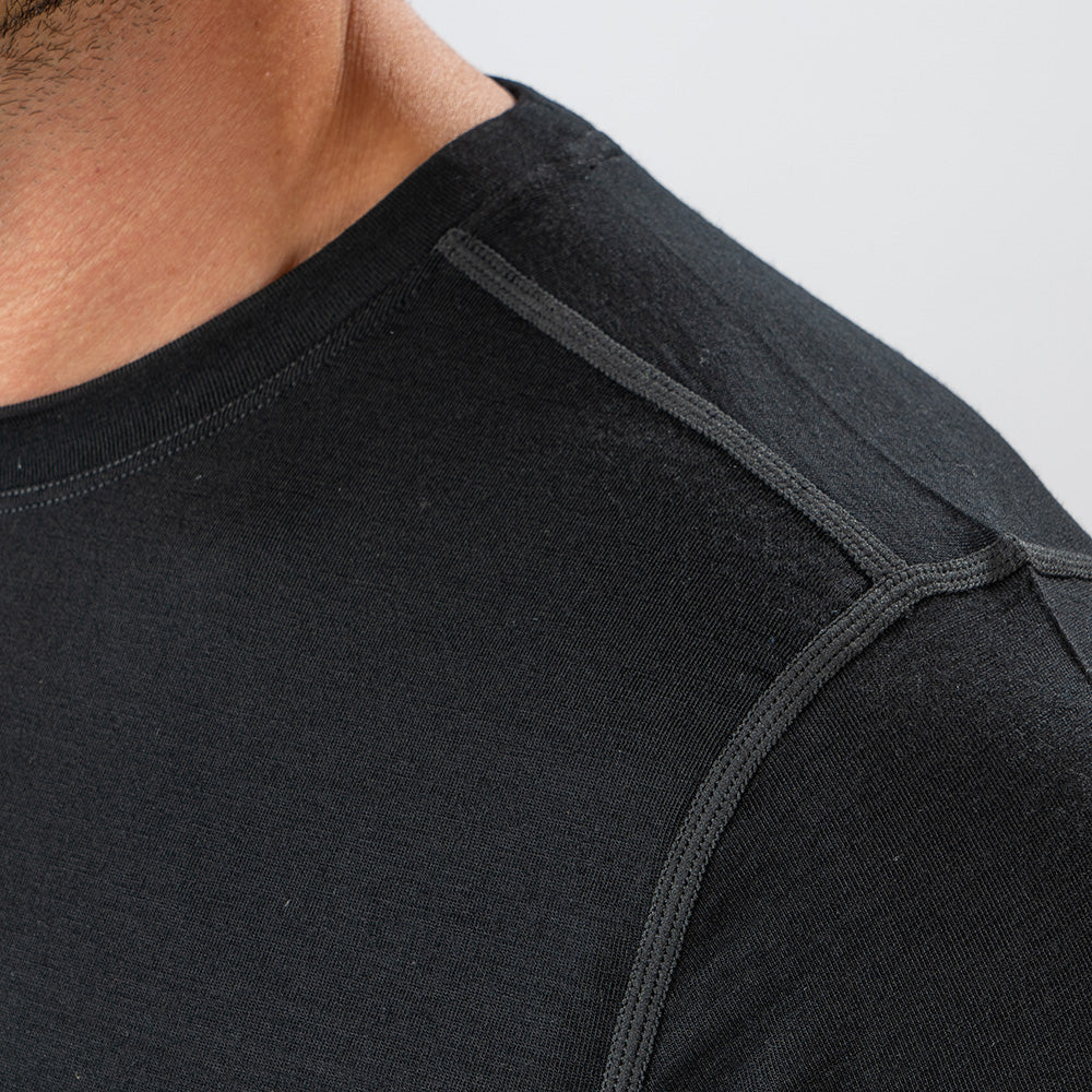 Merino Langarmshirt mit Zip Herren 230 g/m², Nahaufnahme: Textur und verstärkte Nähte des schwarzen Shirts aus 100% Merinowolle sichtbar.