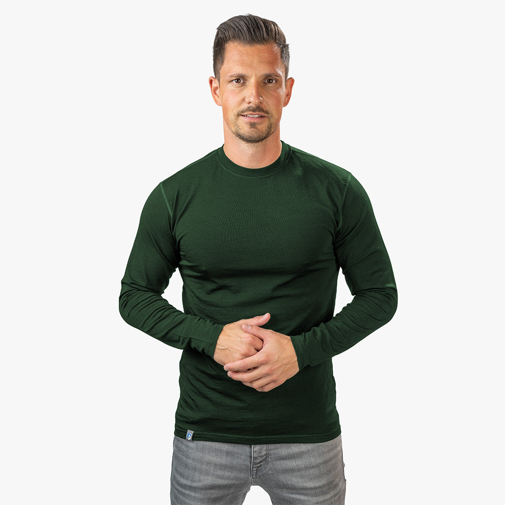 m2 in Dunkelgrün, passend für Outdoor-Aktivitäten, kombiniert mit grauen Jeans vor einem neutralen Hintergrund.