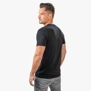 Mann im Merino T-Shirt Herren 150 g/m², blickt über die Schulter. Perfekt für Outdoor-Aktivitäten dank Corespun-Technologie und Merinowolle-Vorteilen.