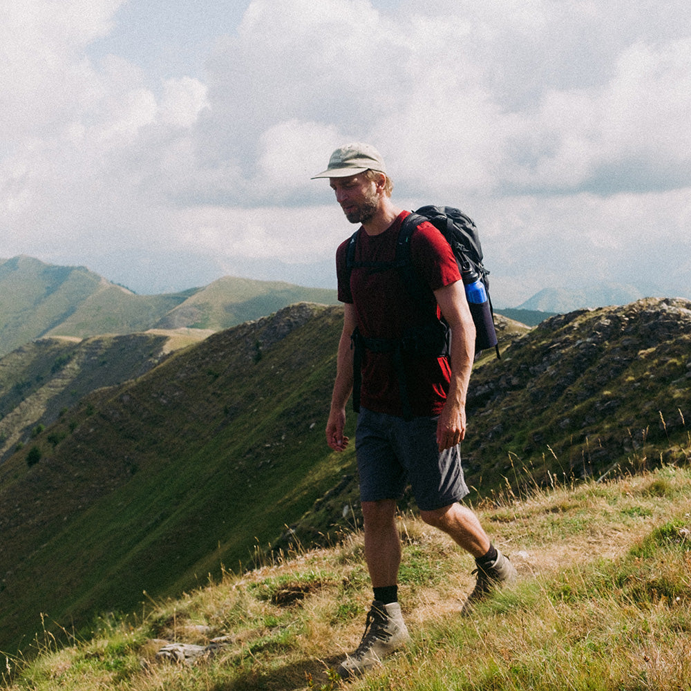 Hiker trägt Merino T-Shirt Herren 150 g/m², ideal für Outdoor-Aktivitäten, mit Corespun Merinowolle für Komfort und Strapazierfähigkeit, während er entlang eines Berggrats wandert.