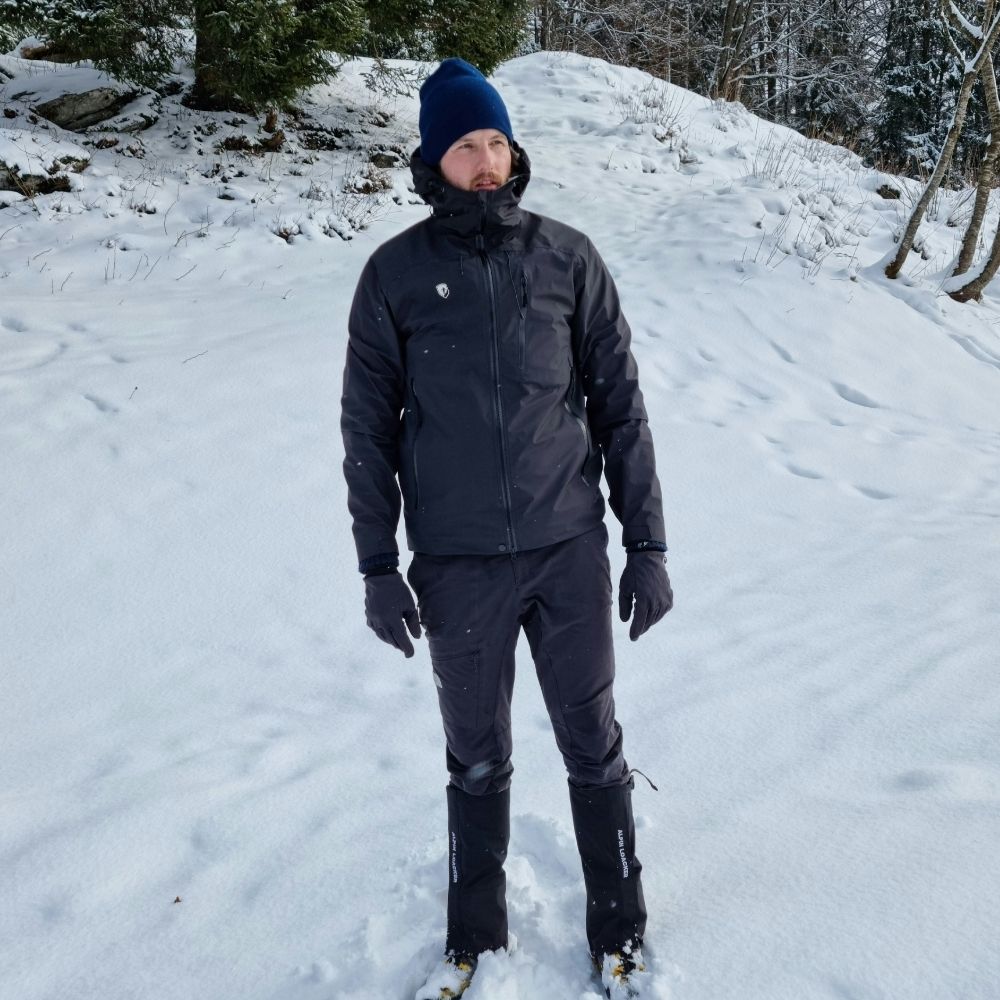 Person in schneebedeckter Landschaft trägt die Herren 3 Lagen Hardshell Regenjacke von Alpin Loacker, ideal für Outdoor-Aktivitäten durch wasserdichte, winddichte und atmungsaktive Eigenschaften.