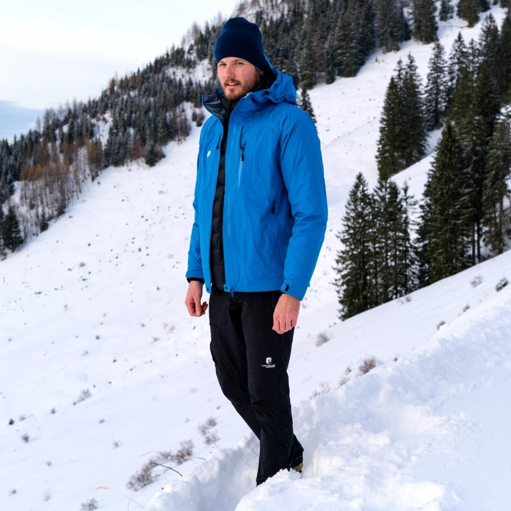 Mann in Herren 3 Lagen Hardshell Regenjacke auf verschneitem Hügel, ideal für Outdoor-Aktivitäten bei jedem Wetter. Perfekt für Alpinloacker Outdoor-Abenteuer.