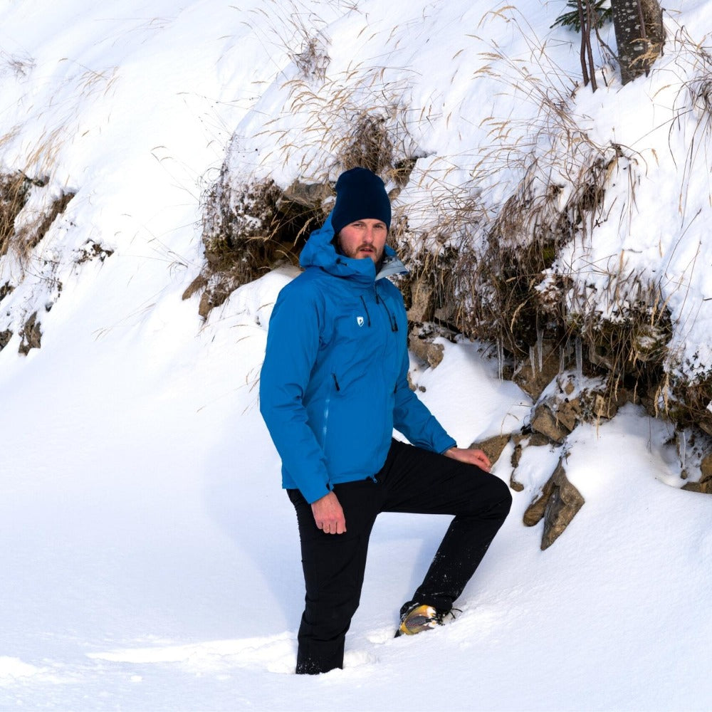 Person in Herren 3 Lagen Hardshell Regenjacke steht kniehoch im Schnee auf einem Hügel, ideal für Outdoor-Aktivitäten bei jedem Wetter.