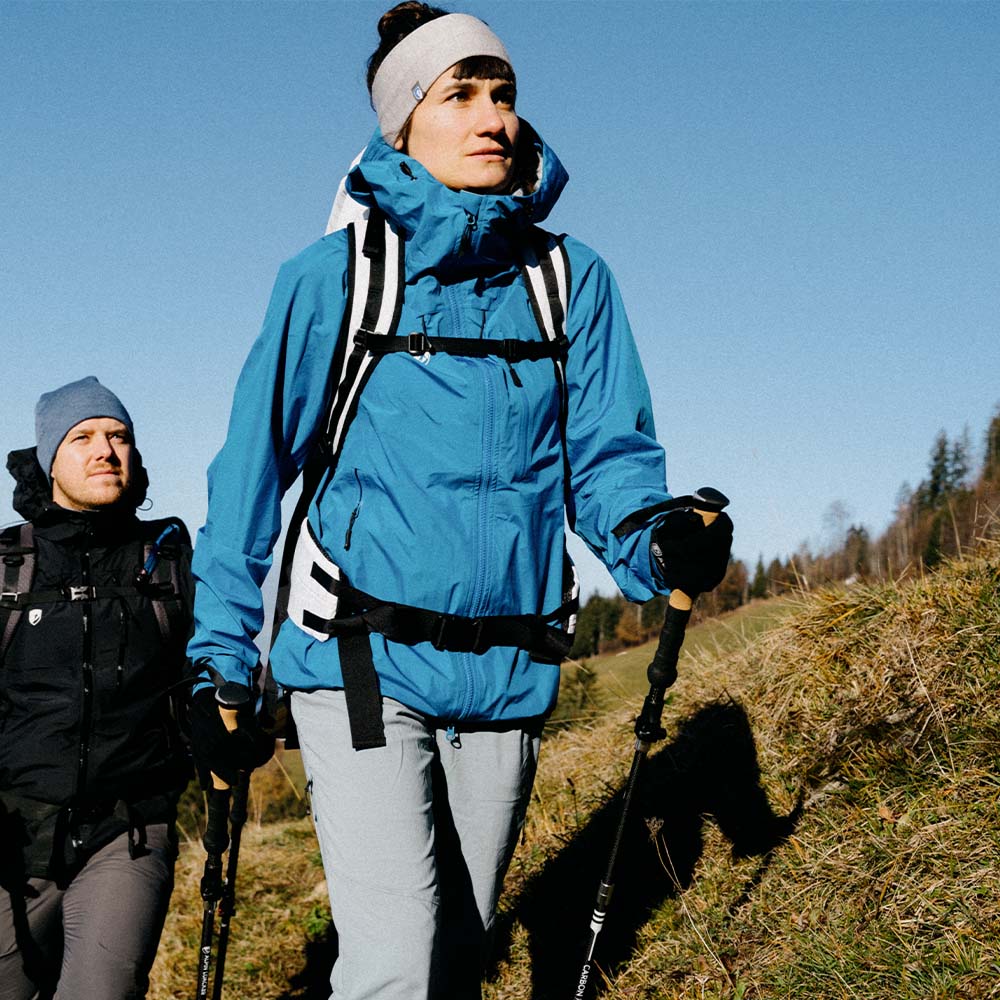 Zwei Wanderer, Frau mit Merino Handschuhe mit Touch Funktion, nutzen Trekkingstöcke auf einem Hügel. Ideal für Outdoor-Aktivitäten dank Wärme und Smartphone-Bedienung.