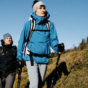 Zwei Wanderer, Frau mit Merino Handschuhe mit Touch Funktion, nutzen Trekkingstöcke auf einem Hügel. Ideal für Outdoor-Aktivitäten dank Wärme und Smartphone-Bedienung.