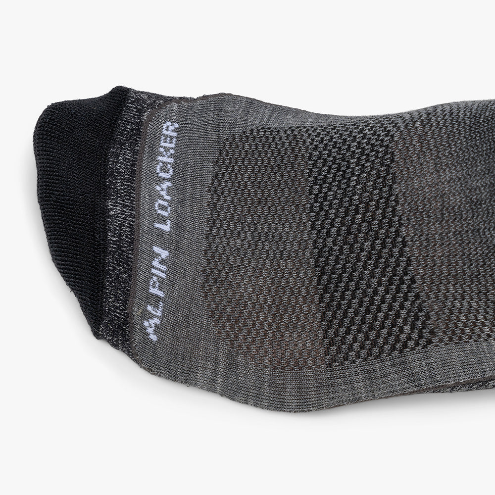 Hohe Merino Ski Socken Herren & Damen, graue Low-Cut-Socke mit schwarzen Akzenten, Mesh-Belüftungszonen, seitlichem Marken-Schriftzug, ideal für Skitouren und Abfahrten.