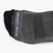 Hohe Merino Ski Socken Herren & Damen, graue Low-Cut-Socke mit schwarzen Akzenten, Mesh-Belüftungszonen, seitlichem Marken-Schriftzug, ideal für Skitouren und Abfahrten.