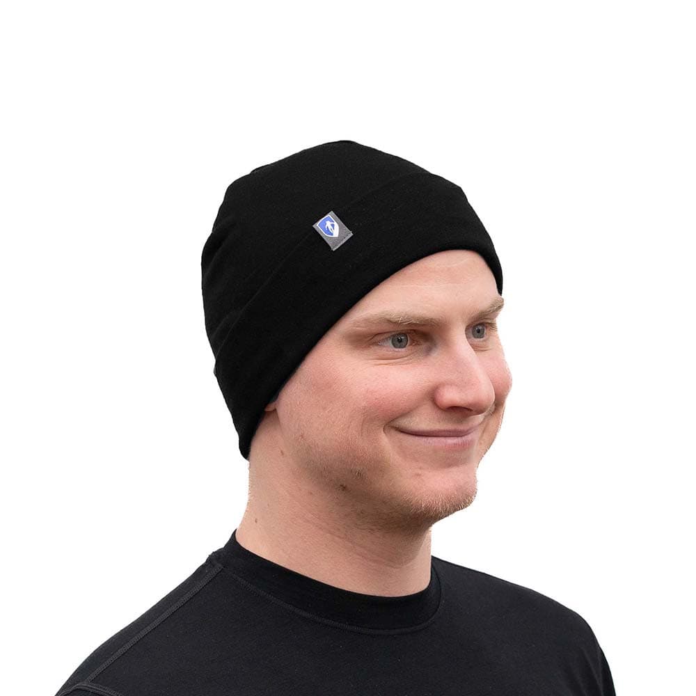 Junger Mann trägt Merino Mütze Herren & Damen 230g/m² aus 100% Merinowolle, ideal für ganzjährigen Komfort und Schutz, lächelnd in schwarzer Kleidung.