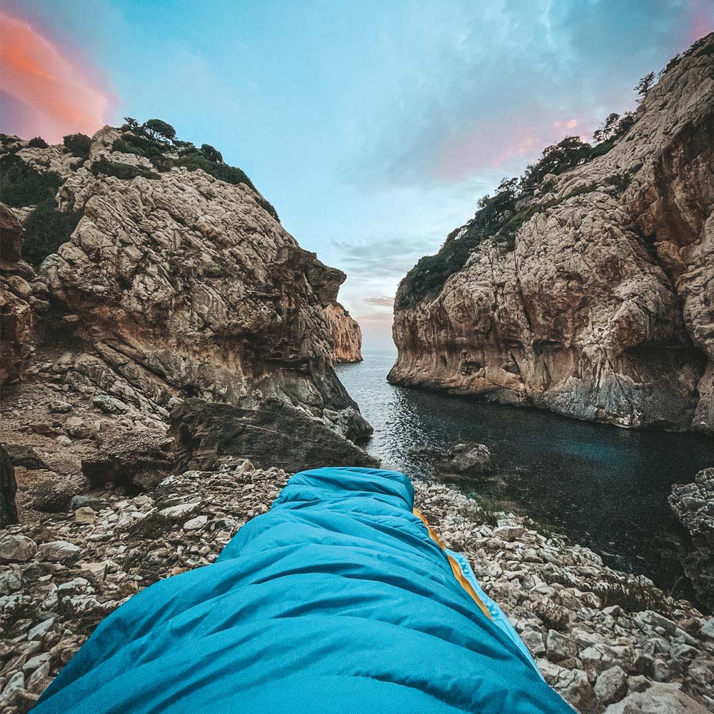 Perspektive aus einem Leichter Sommer Daunenschlafsack, Blick auf felsige Küste und ruhiges Meer. Ideal für Outdoor-Abenteuer, kompakt und ultraleicht für Reisen.
