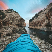 Perspektive aus einem Leichter Sommer Daunenschlafsack, Blick auf felsige Küste und ruhiges Meer. Ideal für Outdoor-Abenteuer, kompakt und ultraleicht für Reisen.