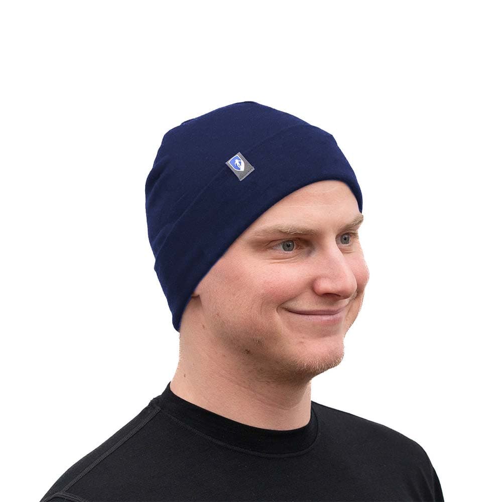 Person mit dunkler Merino Mütze Herren & Damen 230g/m2, lächelnd vor weißem Hintergrund, zeigt die vielseitige, temperaturregulierende Merinowoll-Beanie für Outdoor-Aktivitäten.
