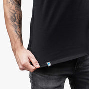 Mann zeigt das Merino Tank Top Herren 150 g/m2 mit sichtbarem gewebtem Etikett; ideal für Outdoor-Aktivitäten dank CORESPUN-Technologie und Merinowolle.