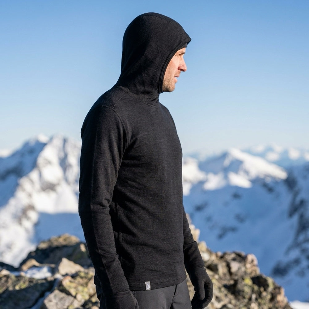 Schwarzer Merino Hoodie Herren 230 g/m² mit Kapuze am verschneiten Gipfel