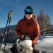 Dame holt Chain Pro 18 Grödel aus ihrem Rucksack; super klein verstaubar und essentiell für Winterwanderungen