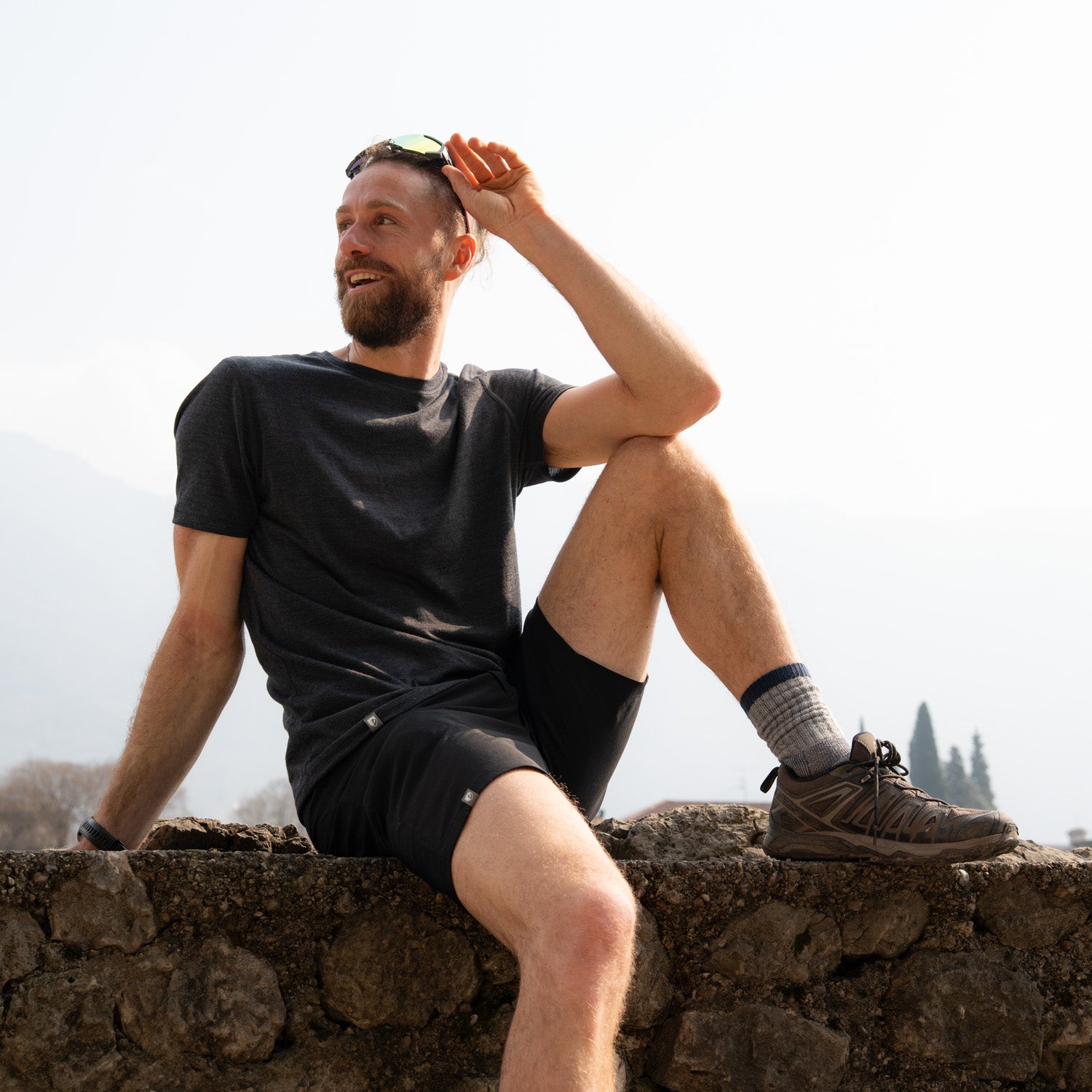 Model sitzt in kurzer Merino Wanderhose von Alpin Loacker auf einer Mauer