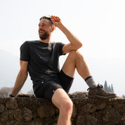Model sitzt in kurzer Merino Wanderhose von Alpin Loacker auf einer Mauer