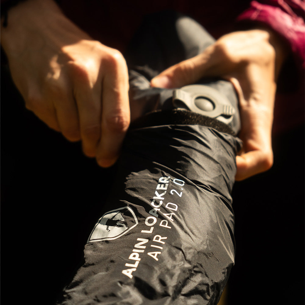 Hände halten eine Ultra leichte Isomatte Air Light, ideal für Outdoor-Abenteuer mit recyceltem RipStop Nylon, leicht und kompakt.