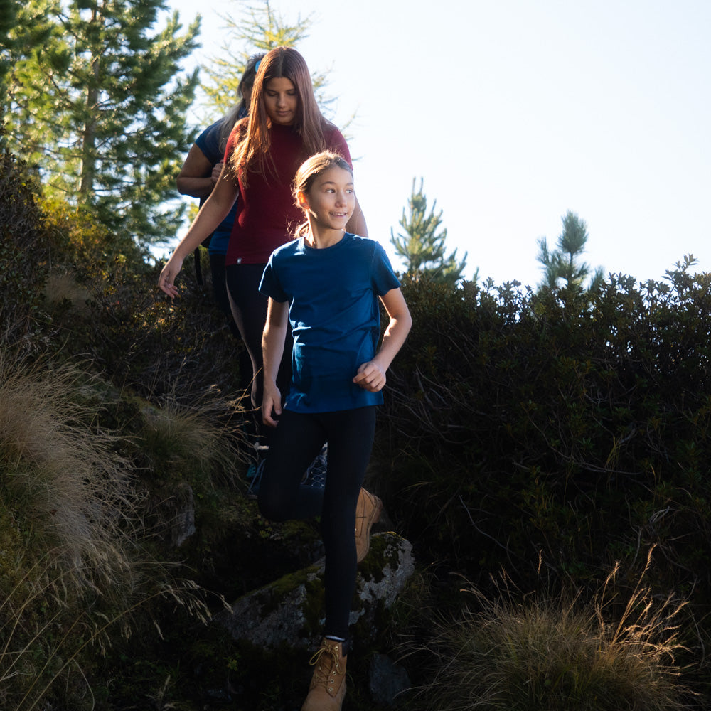 Eine Familie läuft durch die Natur, die Kinder tragen Merino T-Shirts von Alpin Loacker in blau und rot