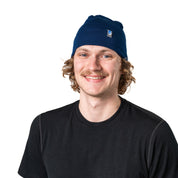 Person trägt eine blaue Merino Mütze Herren & Damen 230g/m² aus 100% Merinowolle, ideal für Outdoor-Aktivitäten, leicht und komfortabel
