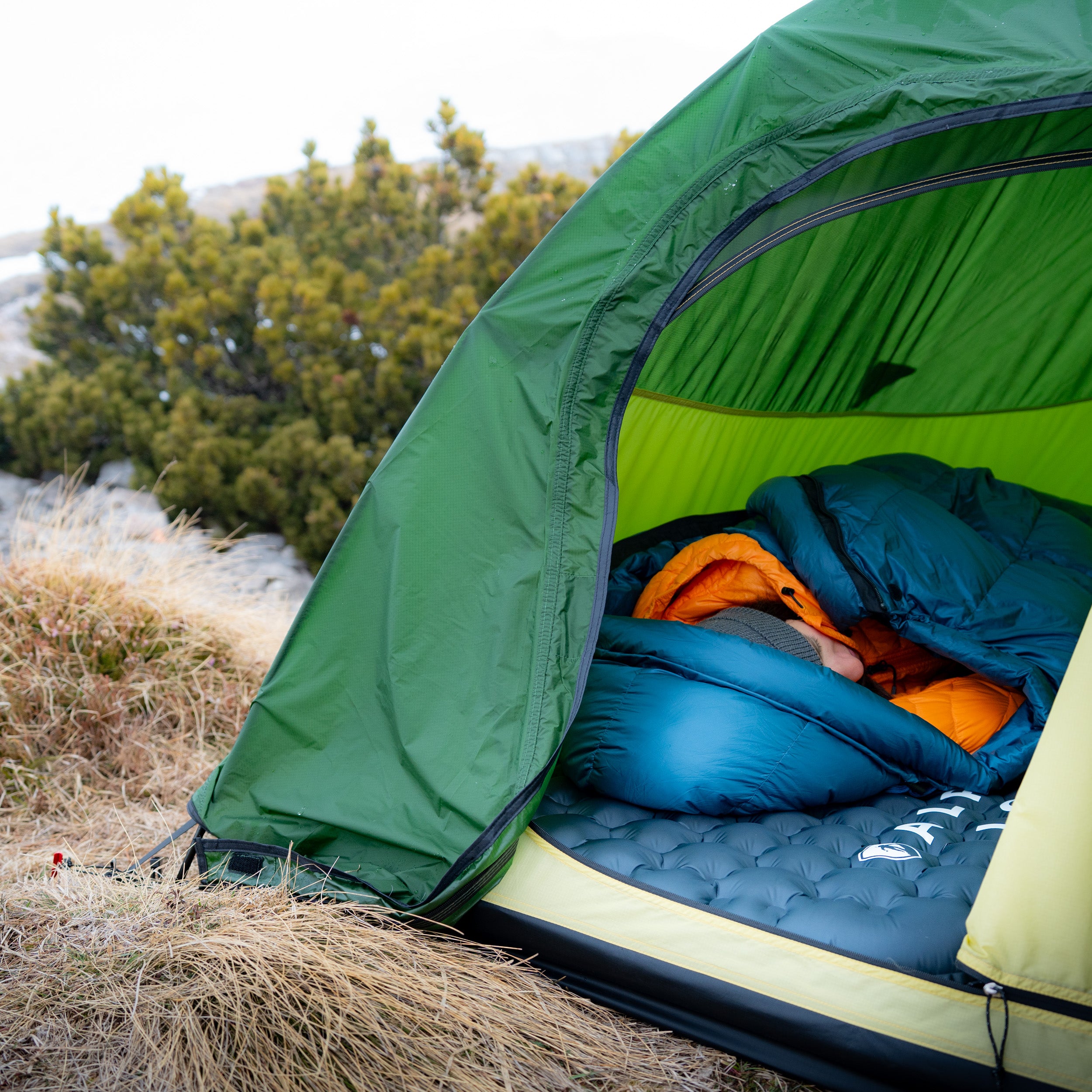 Frau liegt im Zelt bei frostigen Temperaturen auf der R8 Winterisomatte von Alpin Loacker, die einen optimalen Isolationsschutz bei niedrigen Temperaturen bietet