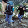 Foldable trail running poles made of carbon, worn by hikers on a rocky path, with ergonomic cork handles and innovative folding mechanism for easy portability.