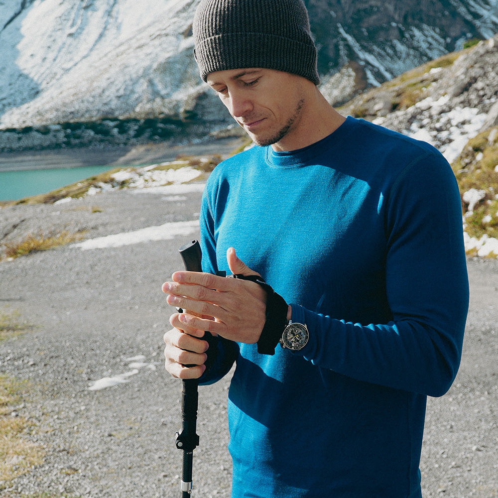 Un homme tient les bâtons de trail running pliables en carbone avec poignées ergonomiques en liège, idéaux pour les activités de plein air et conçus pour les randonneurs et les trail runners exigeants.