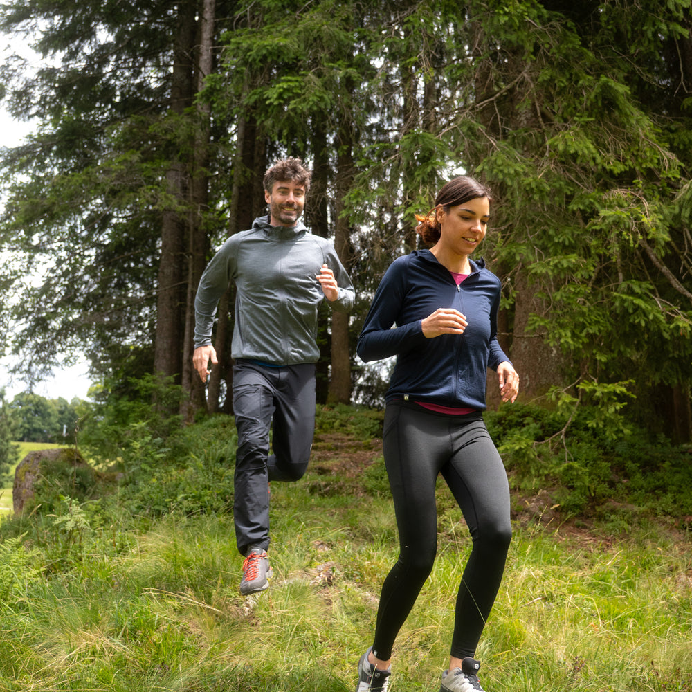 Paar auf Waldpfad in Outdoor-Kleidung, Frau trägt 100% Merinowolle Jacke Damen 160 g/m² - ultrafein, ideal für Outdoor-Abenteuer, wie Wandern oder Trekking.