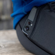 Smartphone in Seitentasche der Merino Leggings/Hose Damen - 290 g/m2, getragen von einer sitzenden Person. Ideal für Bewegung, Reisen und Alltag.