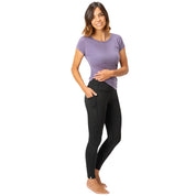 Merino Leggings/Hose Damen - 290 g/m2: Frau trägt atmungsaktive, schwarze Leggings mit Seitentasche; ideal für Yoga, Alltag und Reisen.