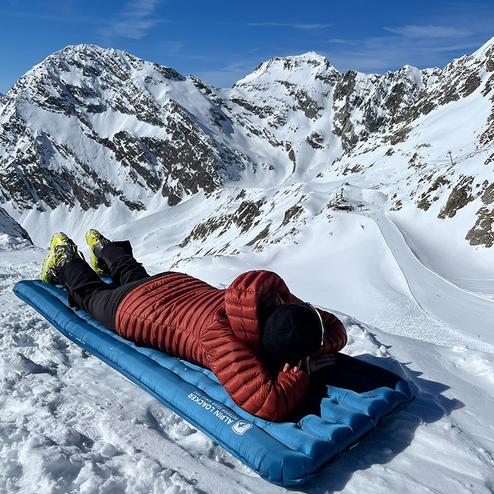 Leichte Isomatte für 4 Jahreszeiten: Person liegt auf dem R5 Pad von Alpin Loacker im Schnee, ideal für Winterabenteuer, hervorragende Isolation, komfortables Design.