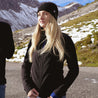 Woman with black jacket and cap, presenting the Merino jacket for women 270 g/m² from Alpin Loacker for outdoor adventures.