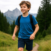 Junge mit Rucksack auf Wanderung im Wald trägt Kinder Merino T Shirt 150g/m², ideal für Outdoor-Abenteuer.