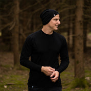 Mann im Wald trägt das Merino Langarm Shirt Herren 150 g/m² von Alpin Loacker, ideal für Outdoor-Aktivitäten, mit temperaturregulierenden Eigenschaften aus Merinowolle.