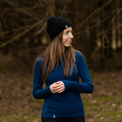 Frau trägt Merino Langarmshirt Damen 150 g/m², ideal für Outdoor-Aktivitäten. Komfort durch CORESPUN-Technologie, ultraleicht und geruchsneutral. Perfekt für Wandern und Alltag.