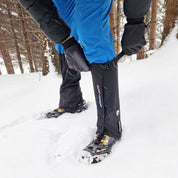 Grödel und Gamaschen Set für sicheren Halt und Schutz bei Winterwanderungen, Trekking und Trailrunning auf Schnee und Eis, gezeigt an einer Person im Schnee.