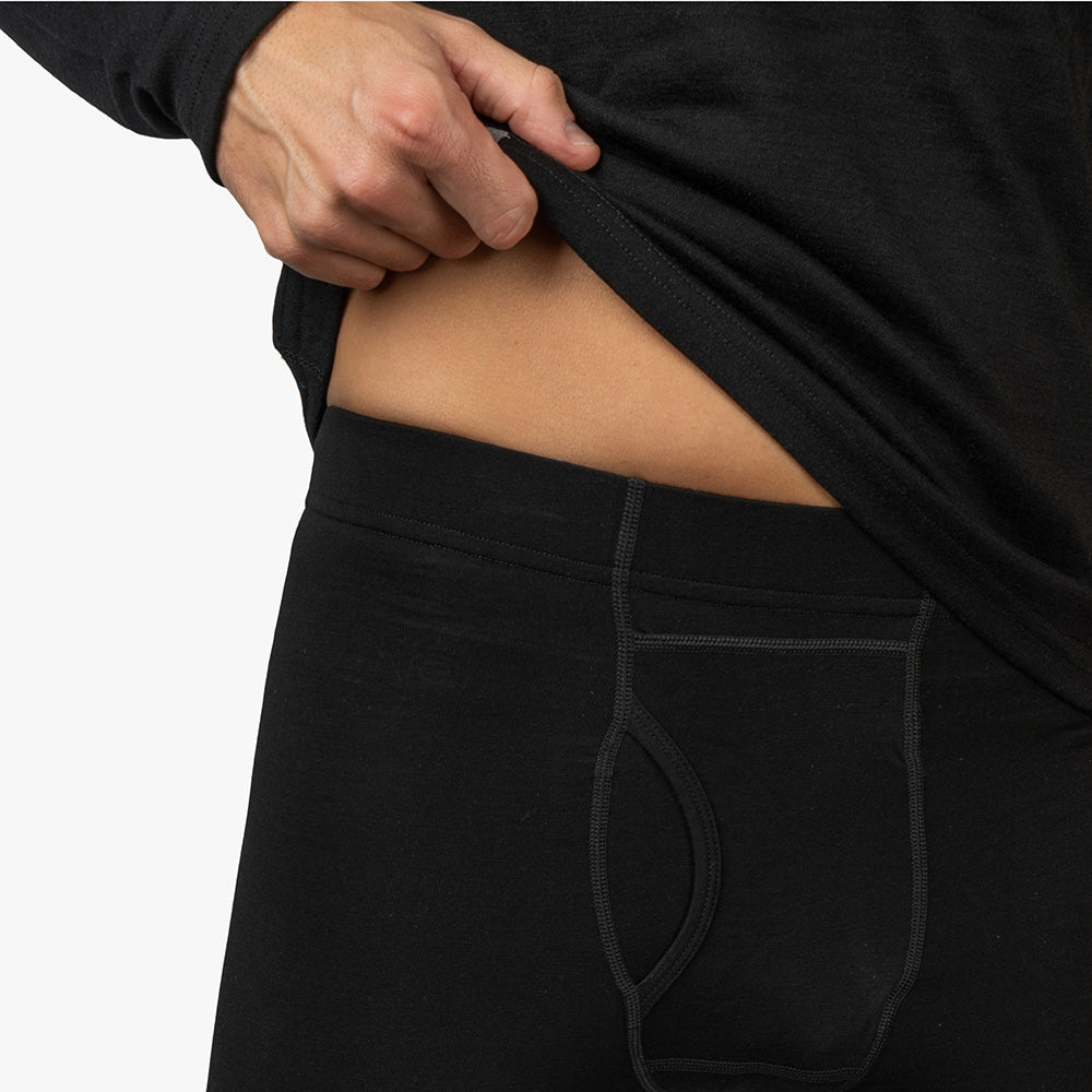 Person zieht lange Merino Unterhose für Herren mit CORESPUN-Technologie aus, ideal für Outdoor-Aktivitäten. Hergestellt aus Merinowolle, bietet sie Komfort und Strapazierfähigkeit.