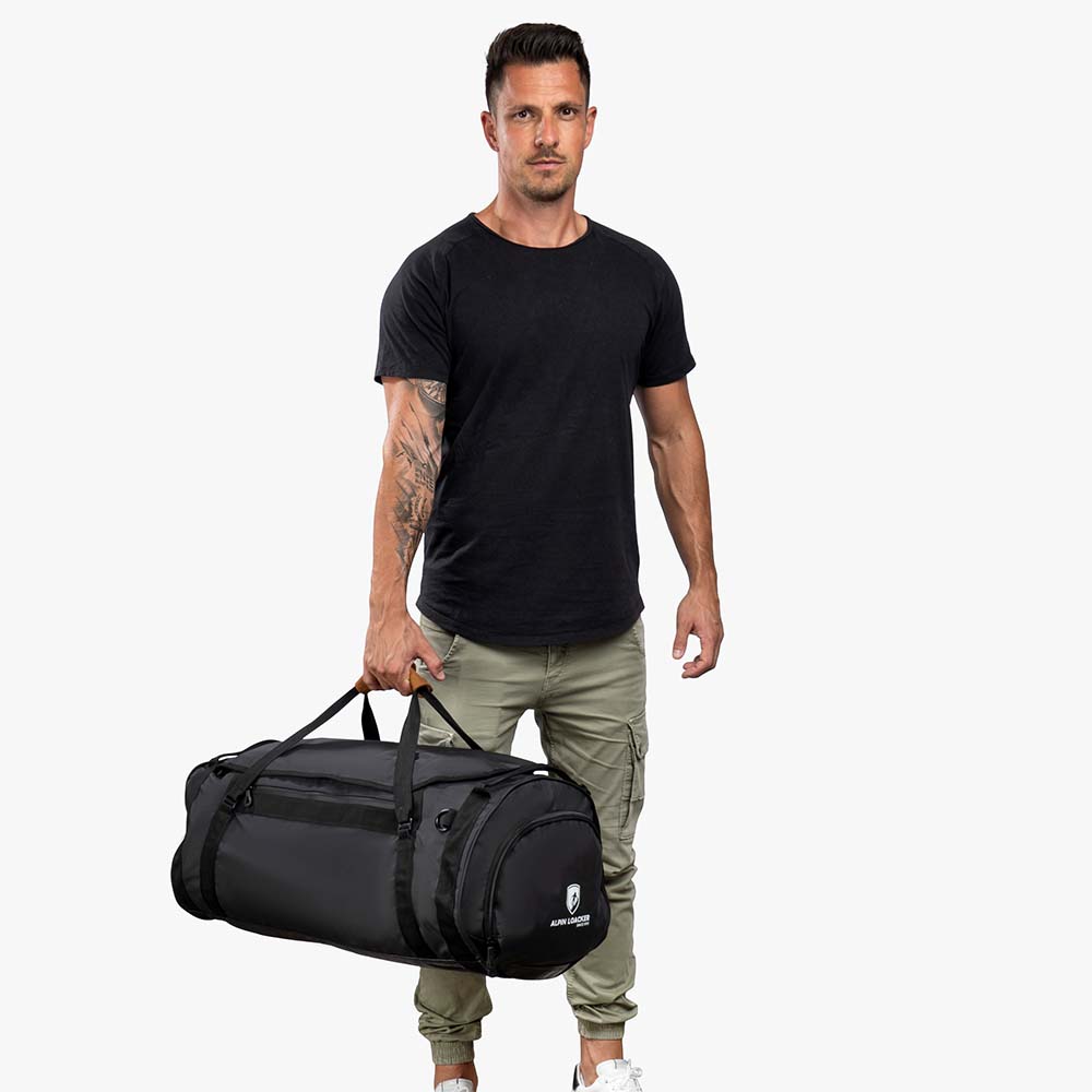 Mann hält Alpin Loacker Reisetasche, Sporttasche & Duffel Bag; geräumig, wasserabweisend, wandelbar in Rucksack, ideal für Outdoor-Abenteuer.