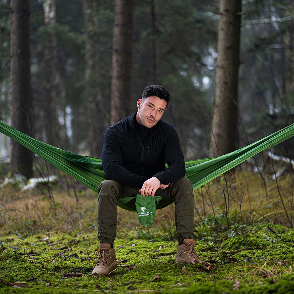 Man zit in het bos op een groene buitenhangmat Alpin Loacker, kampeerhangmat 