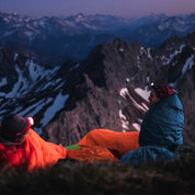 Zwei Personen genießen die Aussicht auf einem Berg in Alpin Loacker Down Pro 3 Jahreszeiten Schlafsack 860g, ideal für kühle Outdoor-Abenteuer.